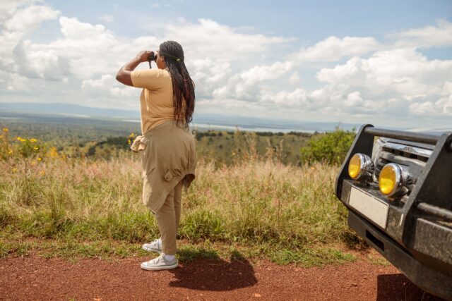 African female taking a road trip using binoculars, looking for wildlife