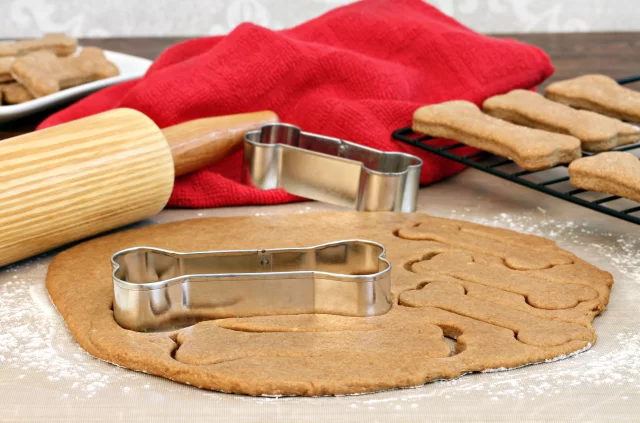 Bone-shaped cookie cutter on cookie dough for dog biscuits