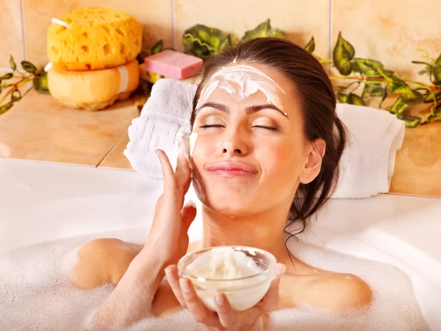 Young lady applying natural face mask in the bath tub