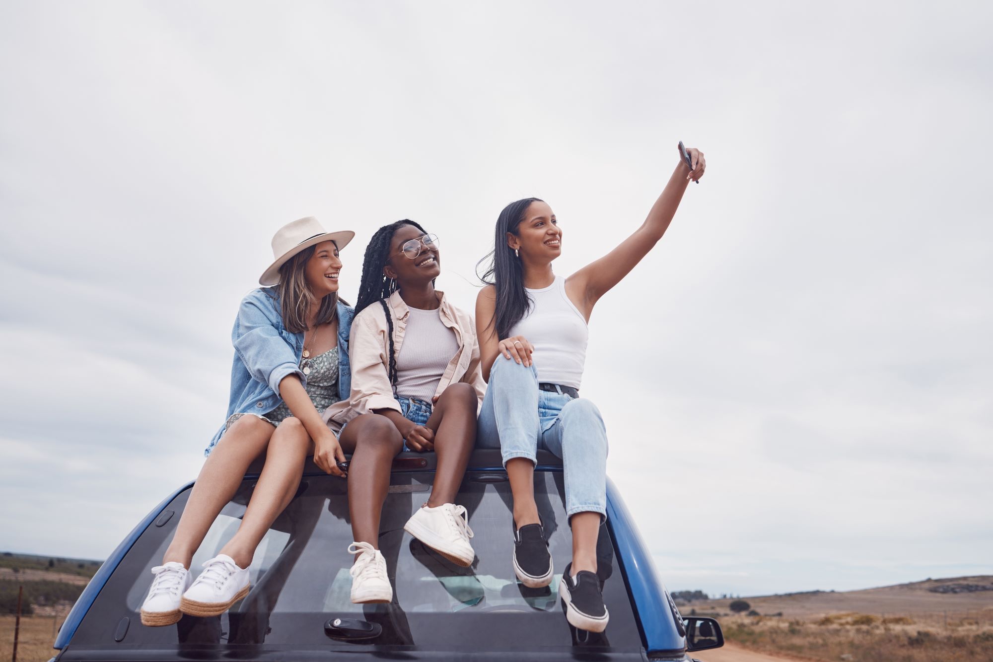 road-trip-selfie-of-women-friends-on-car-roof-with-Why Road Trips Should Be in Your 2024 Travel Itinerary
