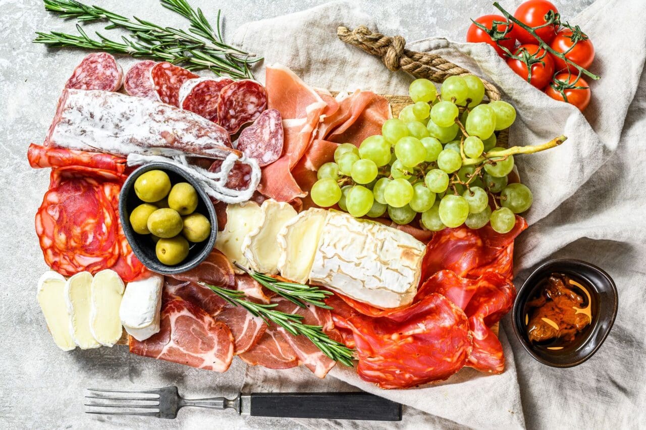 Antipasto cold meat with grapes, prosciutto, slices ham, beef jerky, chorizo salami, fuert