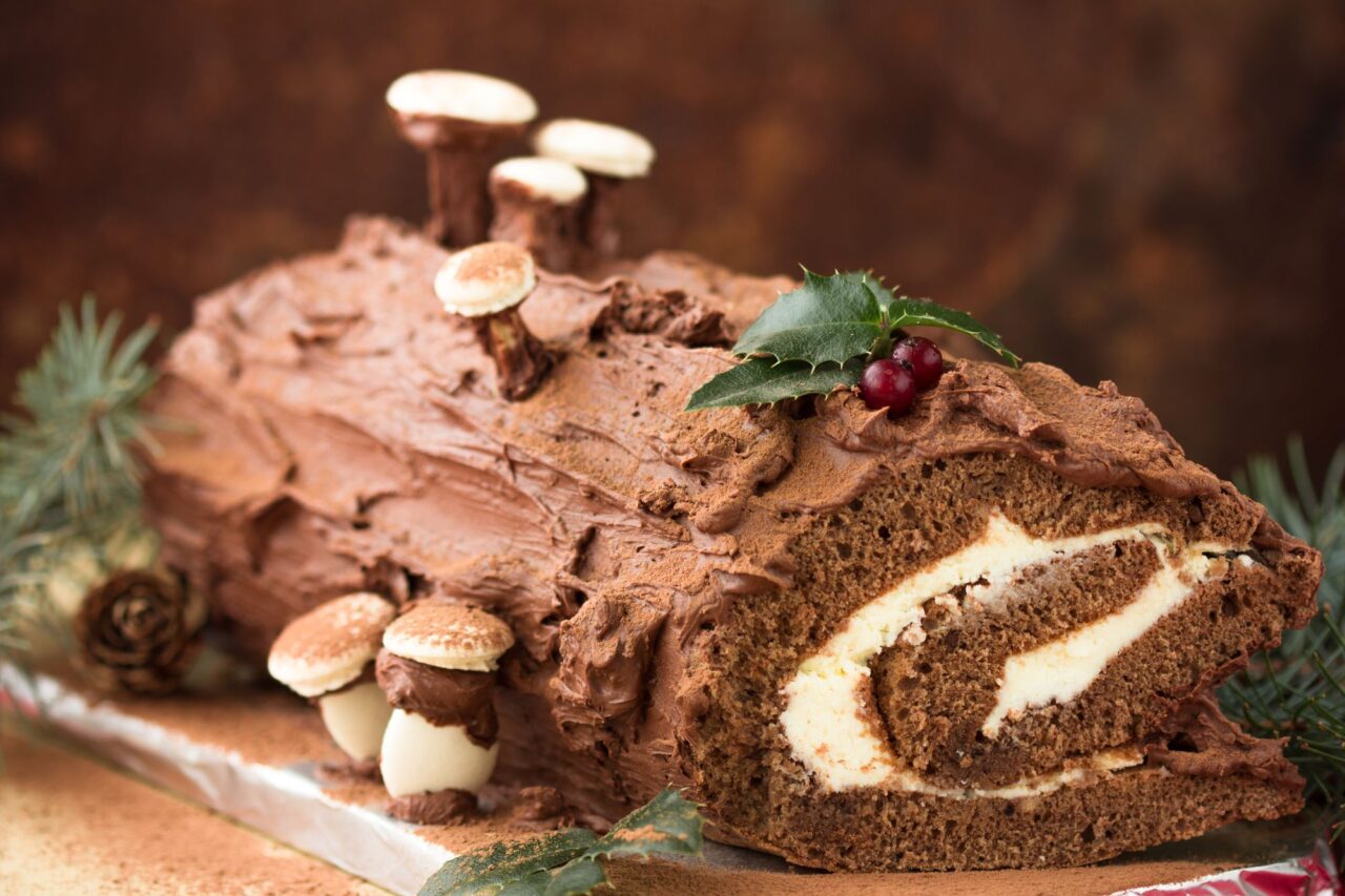 Christmas Yule log cake with edible sweet mushrooms and pine cones