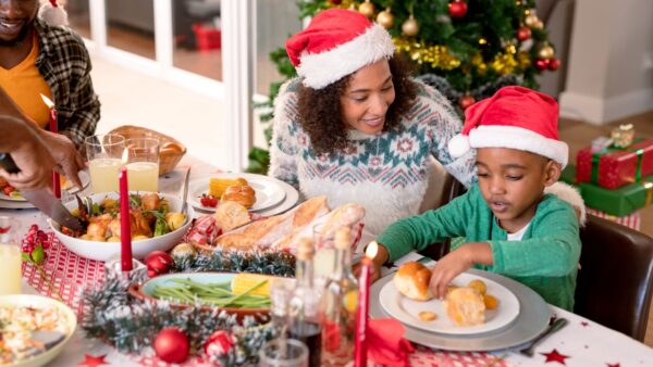 Happy african american mother and son wearing santa hats at christmas table-Authentic Breakfast Meals
