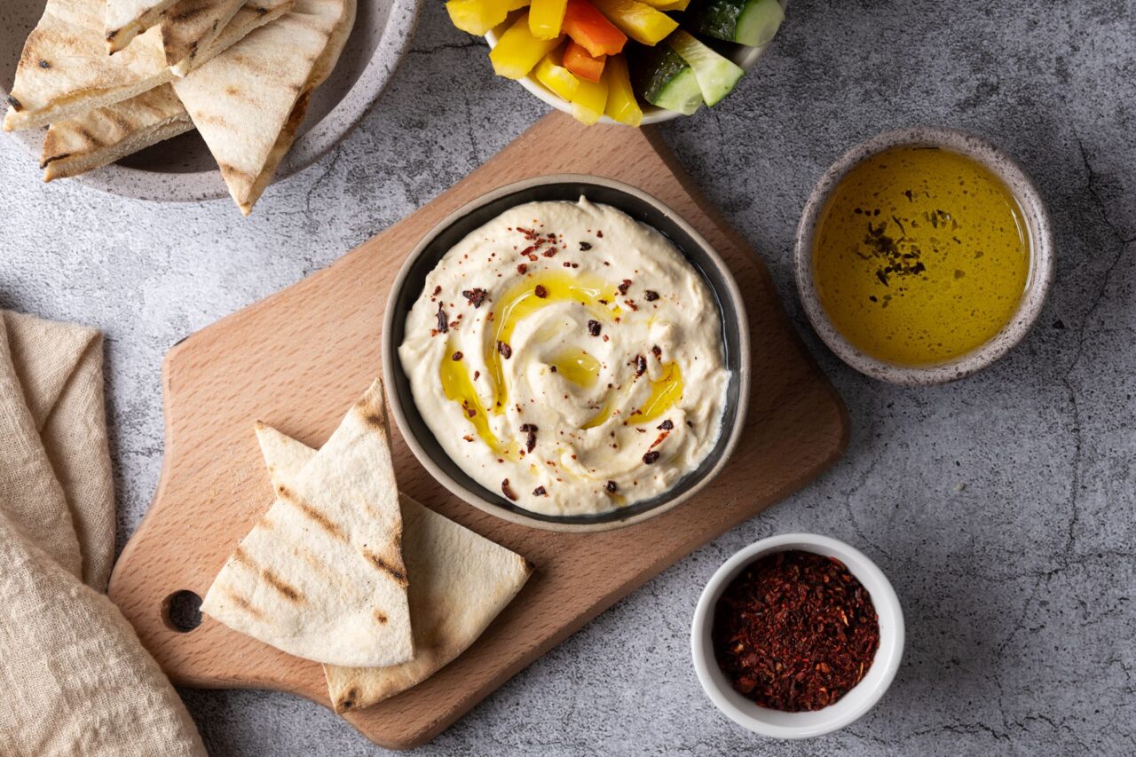Hummus seasoned with olive oil with pita bread on a gray background