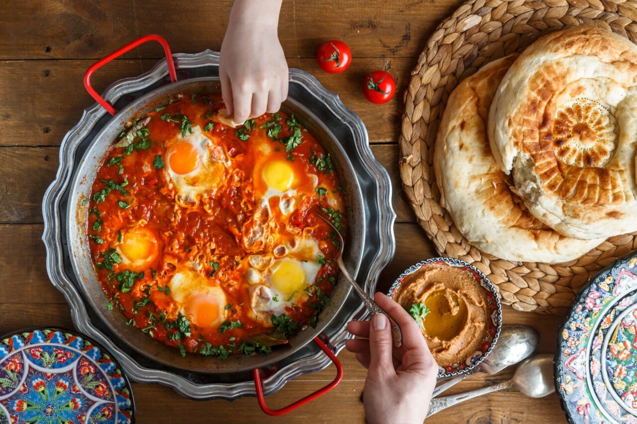 Tasty family breakfast with shakshuka, bread and hummus. Rustic style