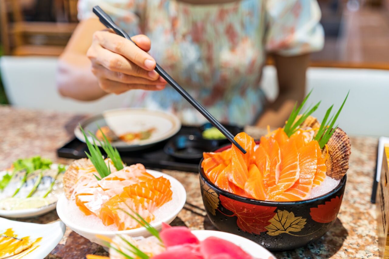 young-asian-woman-eating-sashimi-set-in-japanese-restaurant