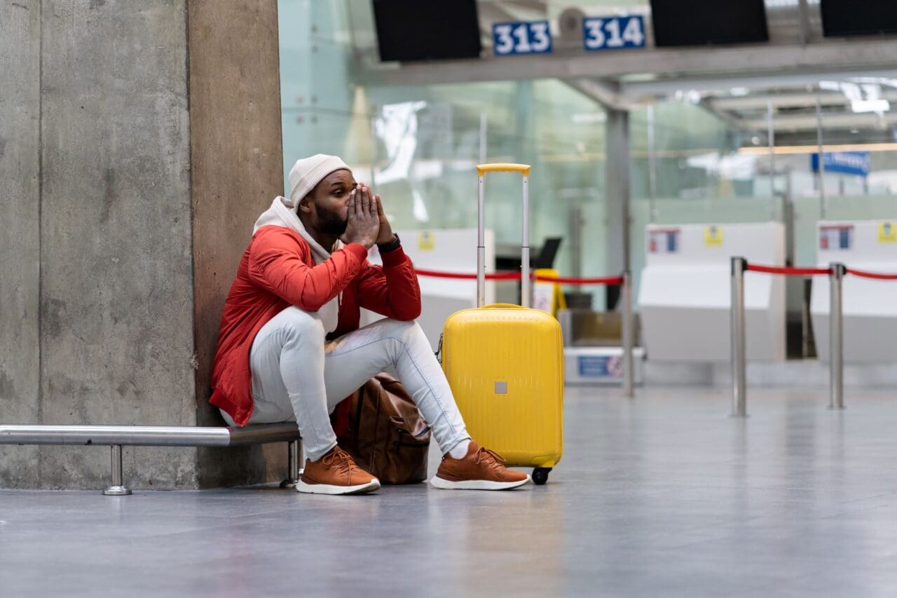 Exhausted African man on a long night connection at airport, waiting for a plane sitting in terminal