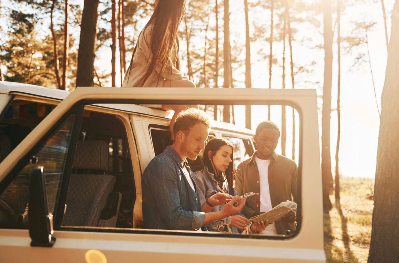 Group of young people is traveling together in the forest at daytime using map