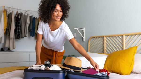 Happy African American young woman packing suitcase at home-Buying Guide for Travel Suitcase