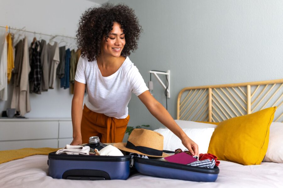 Happy African American young woman packing suitcase at home-Buying Guide for Travel Suitcase