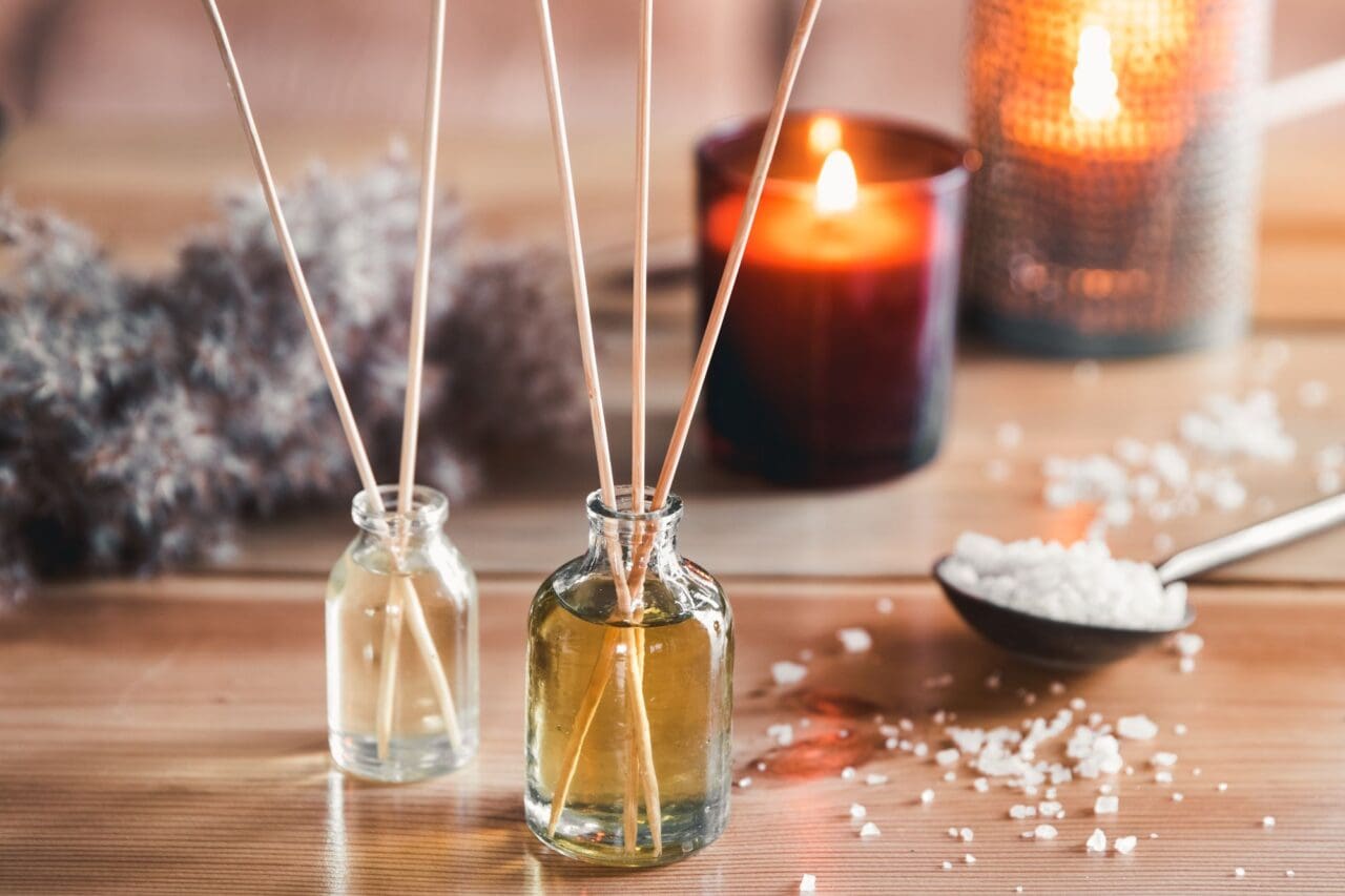 Reed air freshener with candle and eucalyptus branches on tray indoors