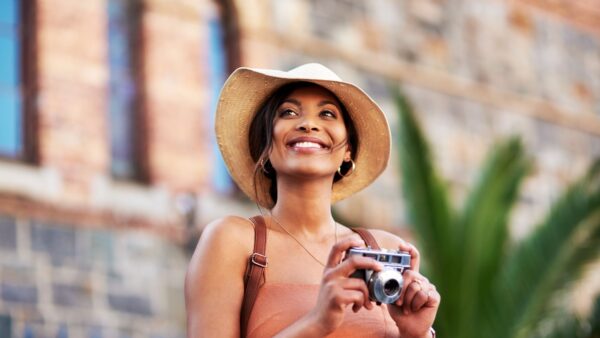 Shot of an attractive young woman taking pictures with a camera while exploring in a foreign city-Best Destinations for Solo Female Travelers